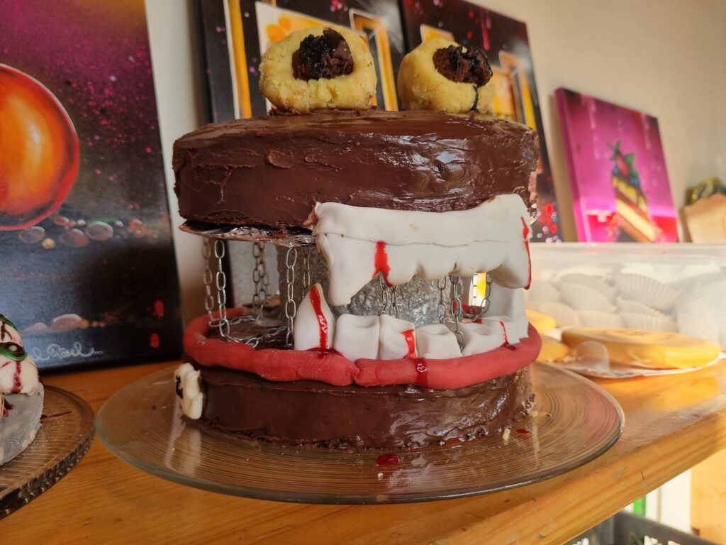 Zweistöckiger Halloween-Kuchen mit Vampirgebiss, ‚Blut‘ und Ketten